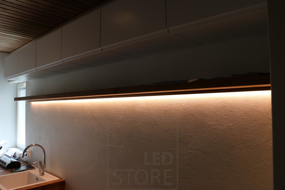 In a utility room, a led strip as a working light, fixed to the bottom of a shelf